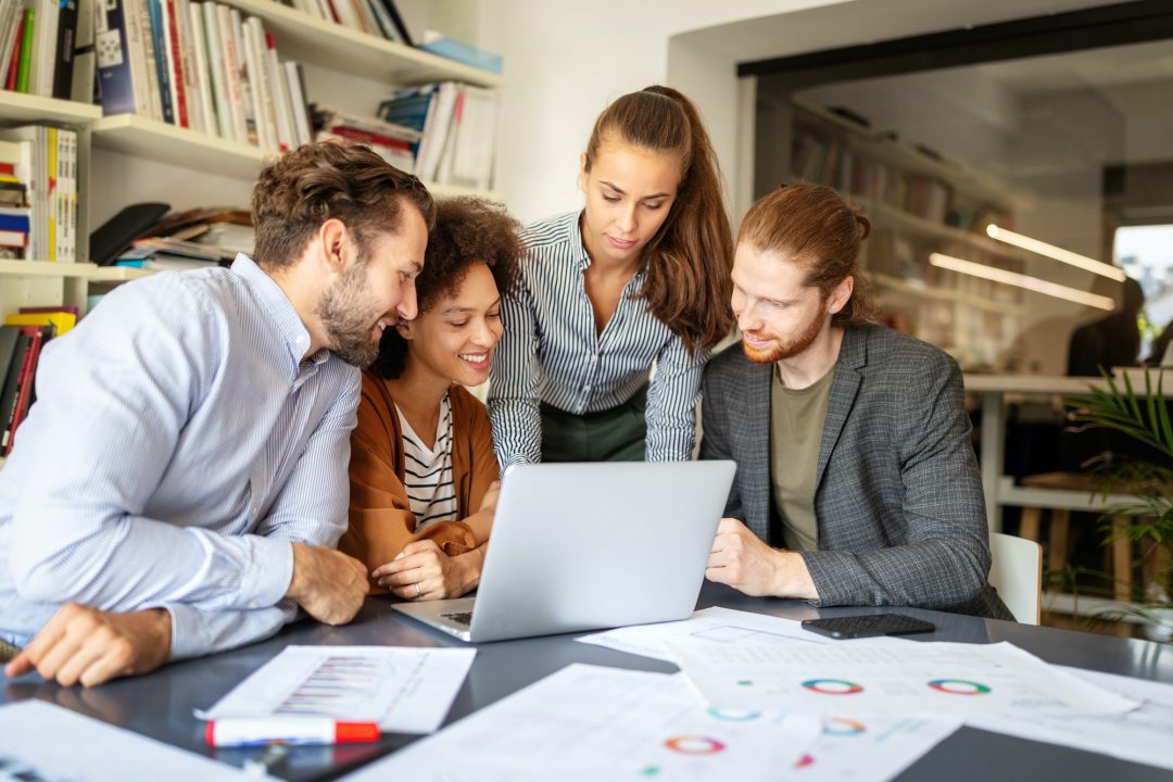 A group of business people looking at a laptop in an office.