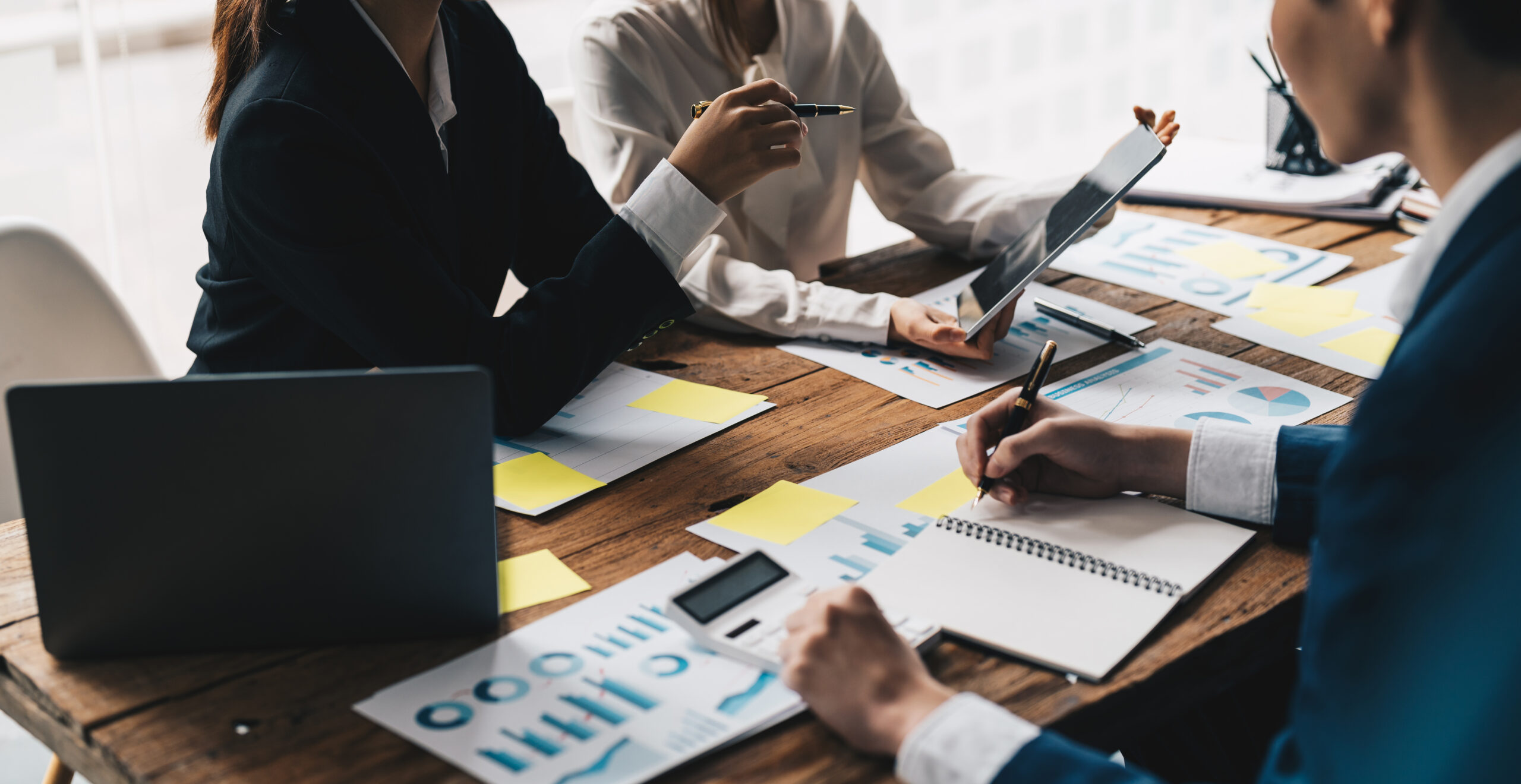 A group of business people working together at a table, utilizing reporting and analytics functionalities in inventory management software.