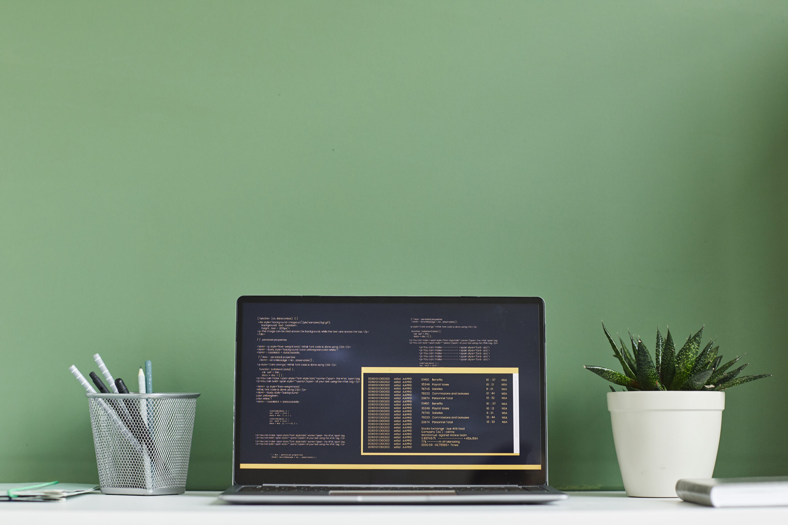 A laptop sits on a desk next to a green wall, showcasing the efficiency of inventory management software.