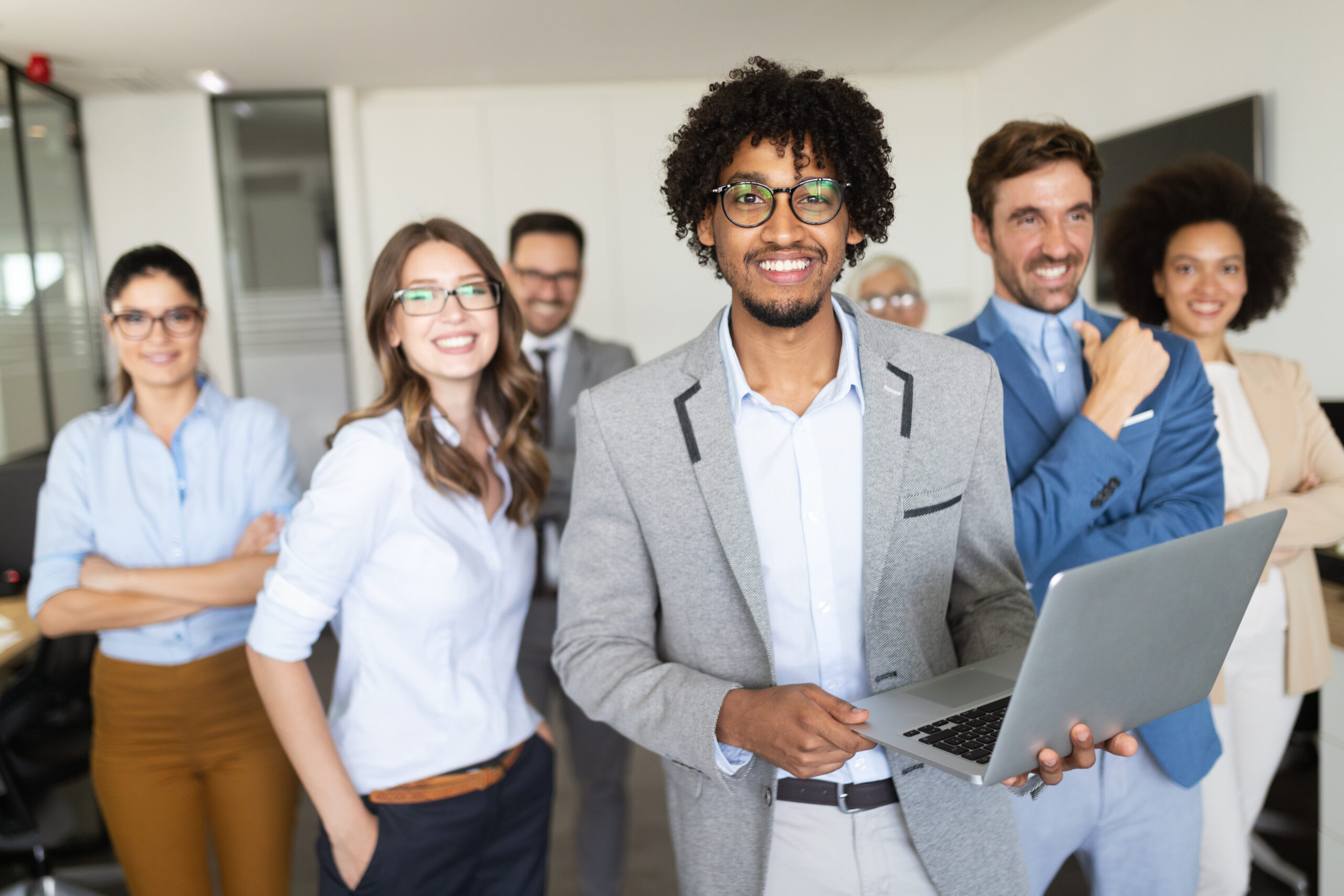 A group of businesspeople exploring integration possibilities between Inventory Management Software and other systems while standing in front of a laptop.